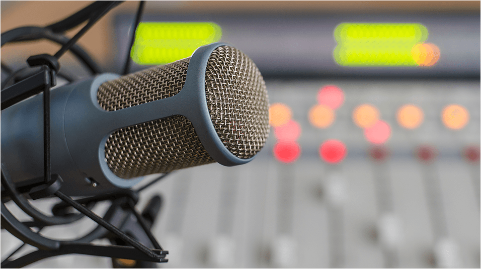 This is an image of a silver microphone on a silver shockmount with a silver mixing desk visible in the backdrop.