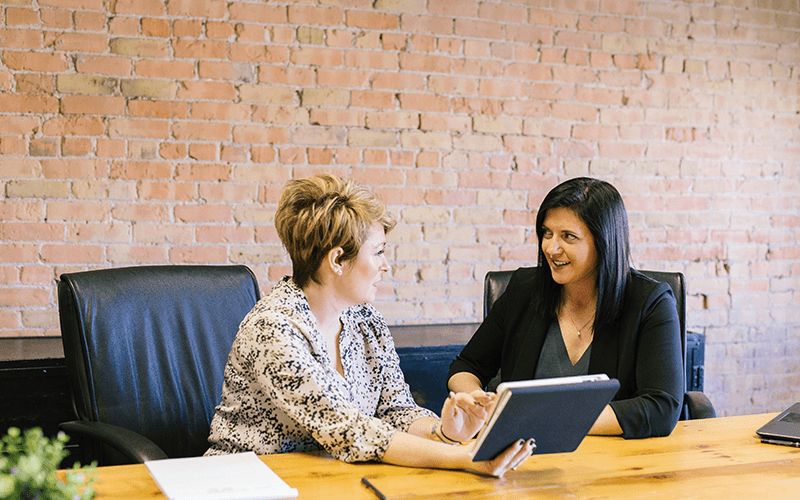 Image shows two women having a meeting within an office.
