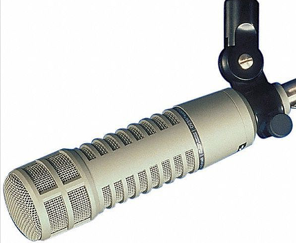 This is a long thin khaki microphone, the Electrovoice RE20, against a plain white backdrop.