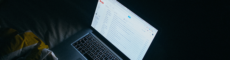 This is a plain black backdrop with a white Macbook screen visible in the centre. the Macbook is open on Gmail.