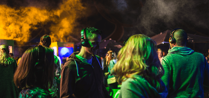 Image shows a crowd enjoying a silent disco at a festival.