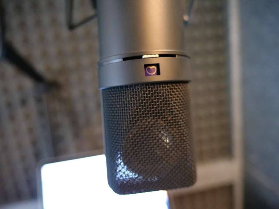 The same background as the previous image, neutral studio, but this time with the Neumann U87 Close Up in the centre of the shot. It is a black mic.