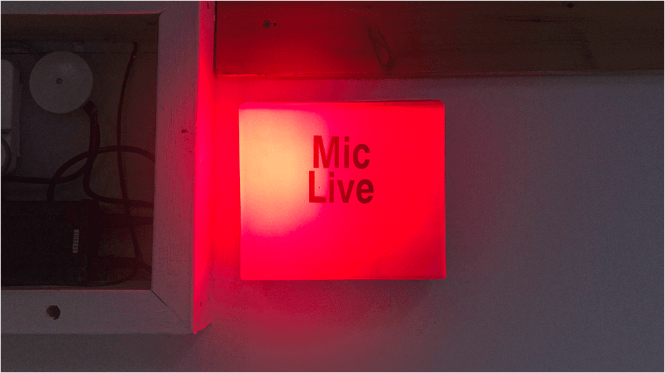 There is a bright red ON AIR box in the centre of the image. The backdrop appears to be a studio.