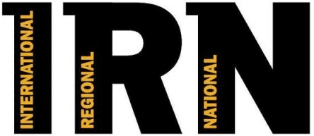 Image shows the logo for Independent Radio News. It features a white background with black capital font that reads IRN. In each letter there are the respective words "international" "regional" and "national" in vertical orange font.