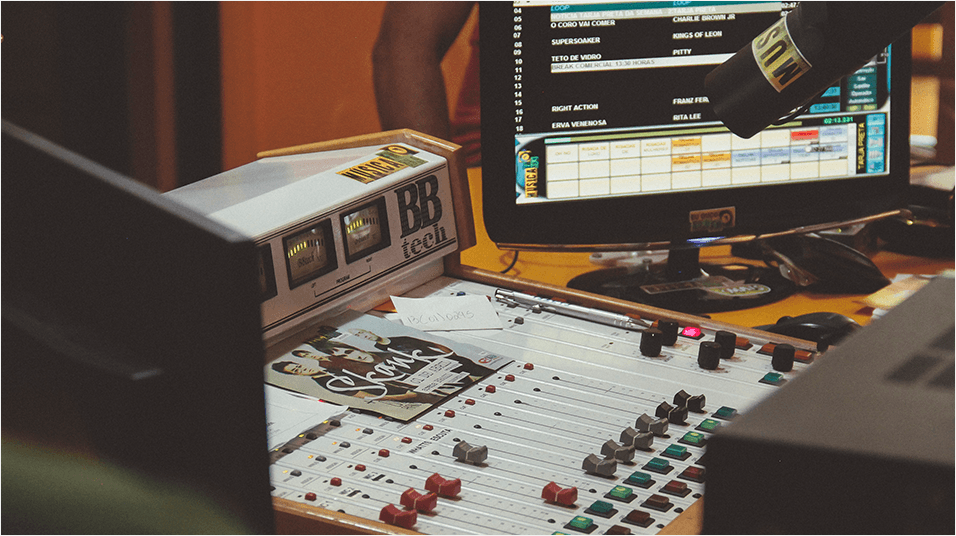 There is a large grey mixer in the centre of the image. On the right is a balck computer with a scrubber visible on the screen.