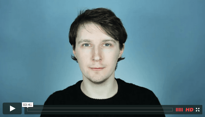 A white man with dark hair and blue eyes sits in front of the camera. Beneath him is a play bar that shows that this is a screenshot from a Youtube video.