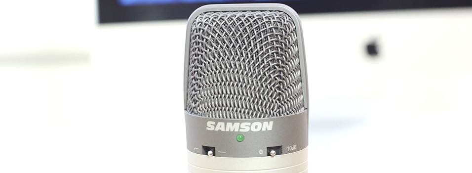 In the centre of the image is the top of a silver Samson C01U Microphone. The back is a white plain backdrop.