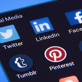 Image shows a close-up of a phone screen which has various social media app thumbnails on the screen.
