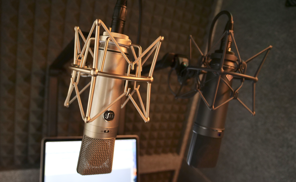 This is a WA87 and U87 microphone side-by-side comparison in the same neutral studio. There is an open computer screen with a plain desktop.
